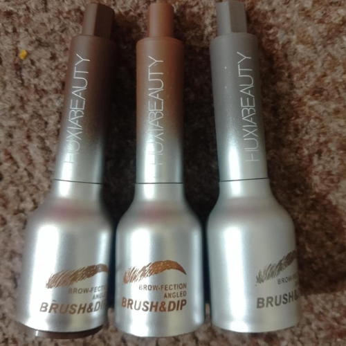 Huxibeauty Brow Fection Angled Brush with three shades of eyebrow gel in silver and bronze packaging.
